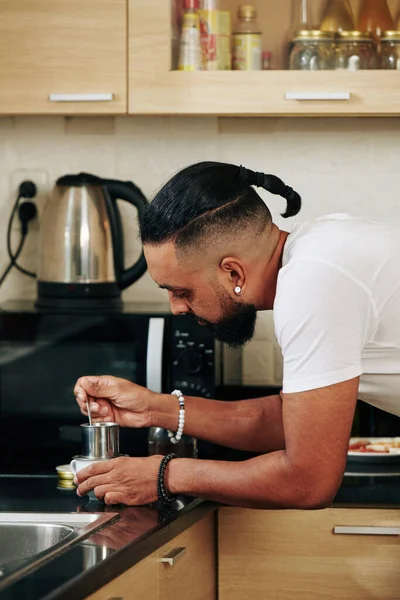 Sabahları mutfak tezgahında içecek hazırlarken Vietnam kahvesi filtresi kullanan yakışıklı bir genç.