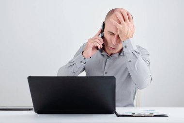İşadamı, başarısız projenin yöneticisi ile telefonda konuşurken yüz hareketi yapıyor