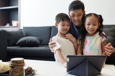 Heyecanlı baba ve iki çocuğu birlikte tablet bilgisayardan yeni animasyon şovu izliyorlar.