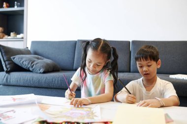 Yetenekli, yaratıcı Vietnamlı erkek ve kız kardeş birlikte resim çizmekten zevk alıyorlar.