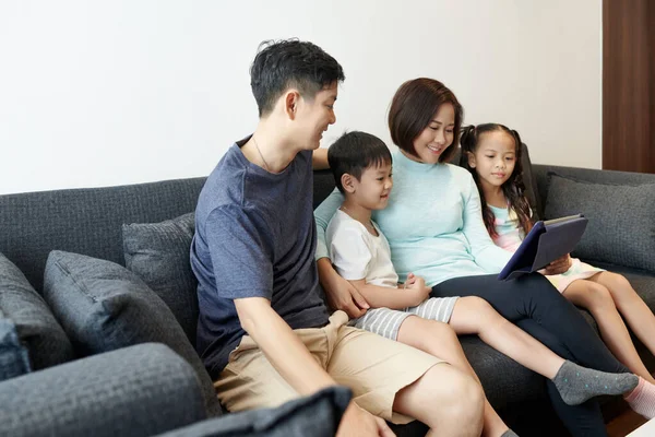 2人の子供と幸せなベトナムの家族は一緒に時間を過ごし アニメーションビデオやブログをデジタルタブレットで見ています — ストック写真