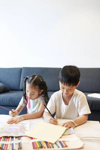富有创造力的未成年兄弟姐妹们坐在家里的桌子旁 用彩色铅笔画画 — 图库照片