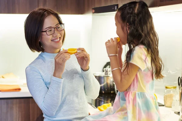 Feliz Asiático Mujer Comer Naranja Rebanada Mirando Lindo Feliz Hija —  Fotos de Stock