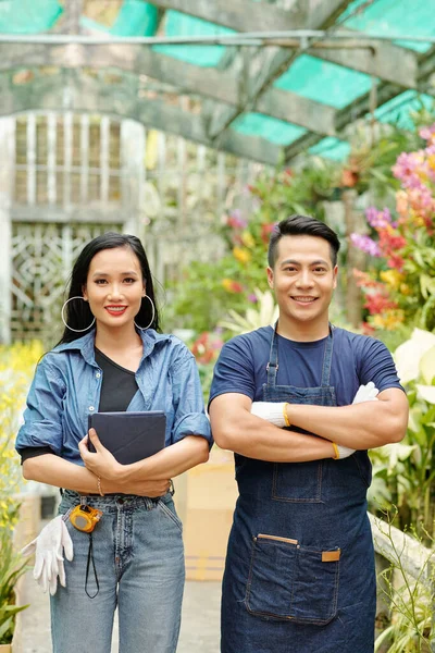幸せな若いベトナム人男性と女性デジタルタブレットが温室に立っている彼らはカメラで働いて笑顔 — ストック写真