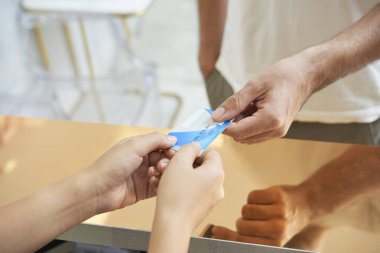 Kaplıca salonu veya klinikte işlem masraflarını karşılaması için resepsiyoniste kredi kartı veren adamın yakın plan görüntüsü