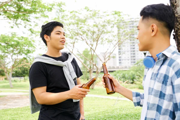 两个朋友喝着酒瓶里的啤酒 在新鲜空气中互相交谈 — 图库照片