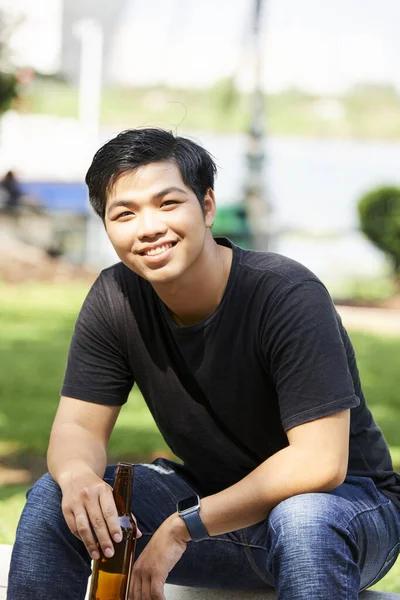 Retrato Joven Asiático Sonriendo Cámara Mientras Está Sentado Banco Con —  Fotos de Stock