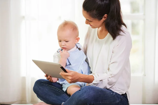 若いですお母さんショータブレットコンピュータとともにアニメーションビデオオンスクリーンへ彼女の赤ちゃん男の子 — ストック写真
