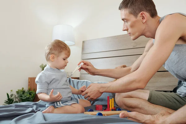 Bambino Seduto Sul Letto Giocare Mentre Suo Padre Misura Sua — Foto Stock