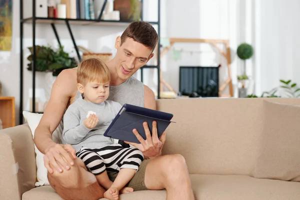 Mladý Otec Sedí Pohovce Svým Dítětem Doma Používá Digitální Tablet — Stock fotografie