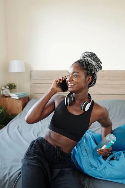 年轻而健康的黑人女人 经过训练 与朋友通电话后 可以躺在床上喝水 — 图库照片