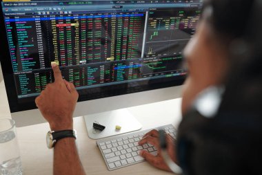 Borsa açıldıktan sonra ne alınacağını planlayan ve finansal verilerle bilgisayar ekranına bakan tüccarlar