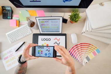 Akıllı telefondan çizdiği logotyle grafik tableti fotoğraflayan tasarımcının elleri