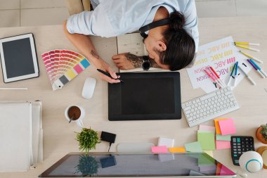 Grafik tasarımcısı dijital kalemle, yukarıdan görünüm ile grafik tabletinde çizerken uyuyakaldı
