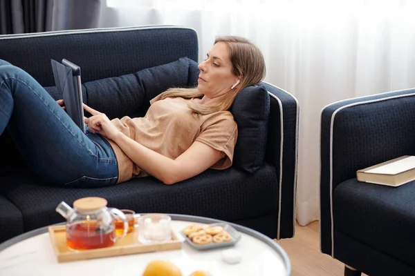 Mujer Bastante Seria Acostado Sofá Uso Aplicación Computadora Tableta Leer — Foto de Stock