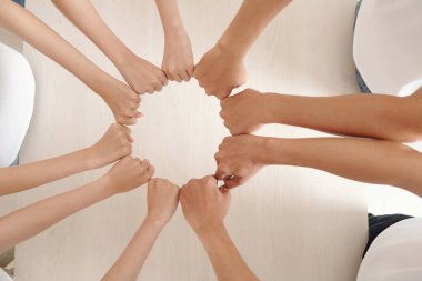 Hayır kurumu gönüllülerinin elleri sıkılmış yumruklarla daireler çizerek destek ve birlik içinde.