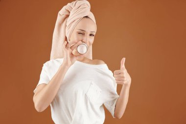 Mutlu genç kadın sabah duşundan sonra nemlendirici dudak maskesi kavanozunu gösteriyor.