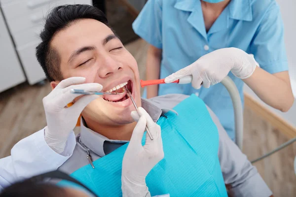 Zubař Léčení Zubů Mužského Pacienta Když Zdravotní Sestra Uvedení Slin — Stock fotografie