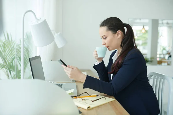 Jovem Empresária Séria Bebendo Café Lendo Mensagem Texto Colega Trabalho — Fotografia de Stock