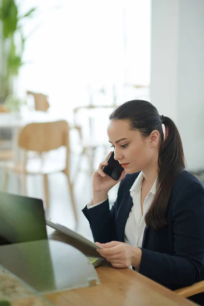 Porträtt Seriös Ung Kvinnlig Entreprenör Talar Telefon Och Läsa Dokument — Stockfoto