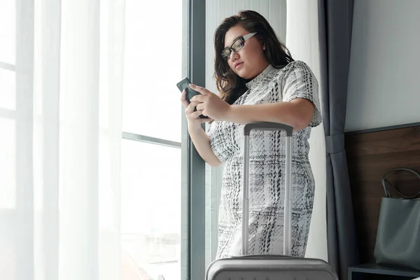 Serious Young Woman Standing Hotel Room Next Her Luggage Using — Stock Photo, Image