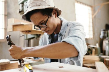 Marangoz mobilya yaparken odun parçalarını yüzeyden çıkarmaya odaklanmıştı.