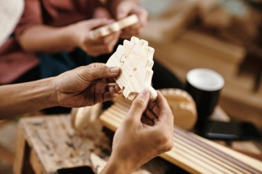 Marangozun elleri, müşteri için yarattığı tahta yapbozu kontrol ediyor.