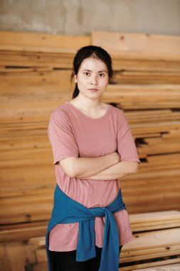 Kendine güvenen genç kadın marangozun portresi. Kollarını kavuşturup kameraya bakıyor.