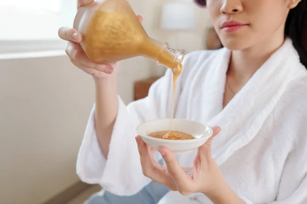 浴衣に身を包んだ若い女性が 黄金の保湿化粧水をソーサーに注ぐ姿 — ストック写真
