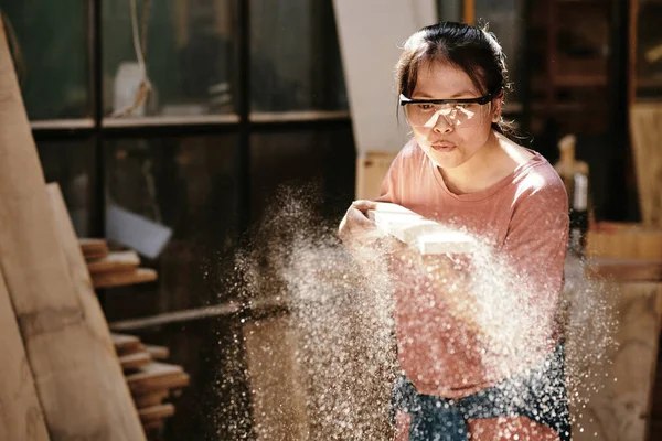 Mladá Žena Tesařka Ochranných Brýlích Odfoukává Piliny Dřevěného Prkna — Stock fotografie