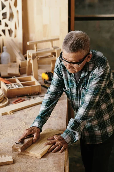 シニア男でゴーグル作業木のブロックで作業でワークベンチ — ストック写真