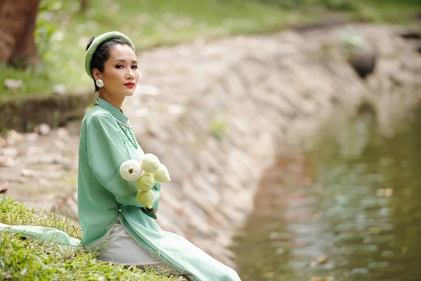 美丽迷人的年轻越南女人 穿着欧代服装 头戴名为 Khan Dong 的头饰 坐在荷花池塘边 — 图库照片