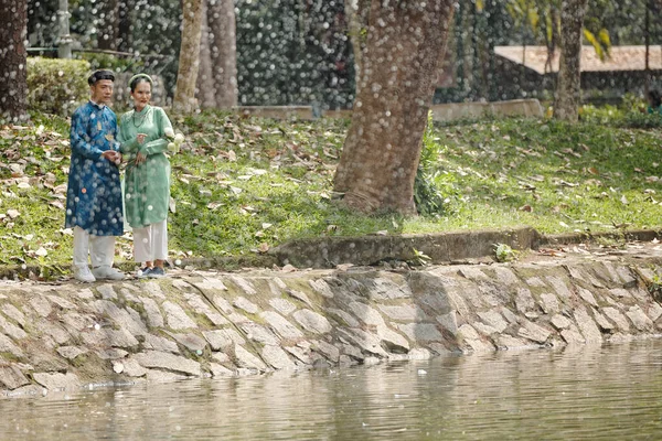 雨天刚结婚的一对越南年轻夫妇在城市公园池塘边散步 — 图库照片