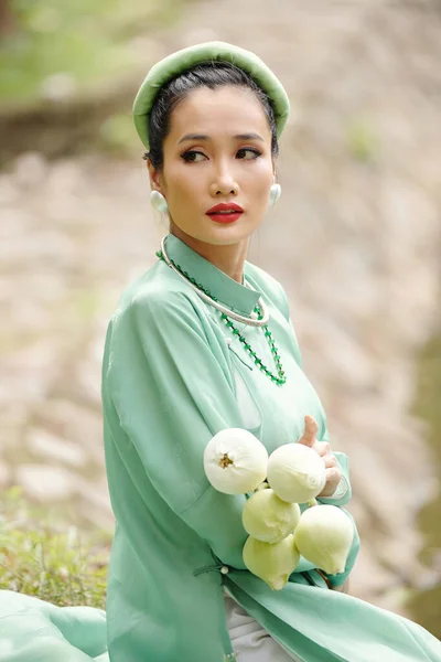 穿着薄荷裙 头戴头巾 手里拿着一束荷花的严肃年轻女子的画像 — 图库照片