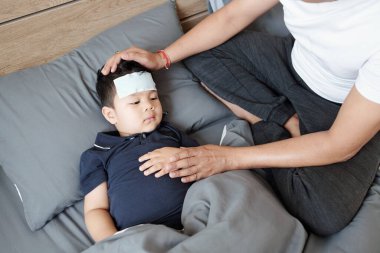Baba, hasta oğlunun yanında yatmış, alnında jöle bandıyla ateşler içinde yatıyor.