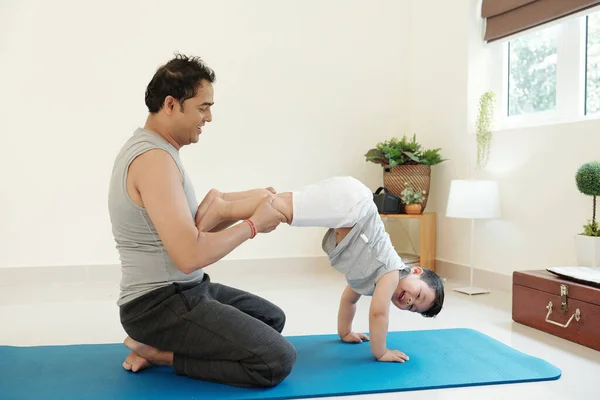 Cheerful Father Helping His Laughing Child Practicing Handstand Home — Foto Stock