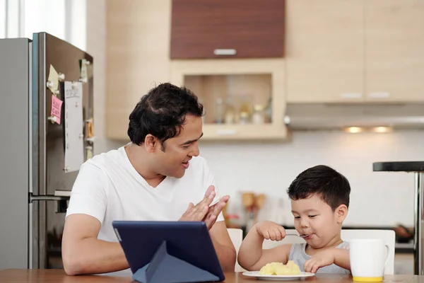 インド人男Clappingへ彼の息子食べるプレートのマッシュポテトのプレートで一人でキッチンテーブル — ストック写真