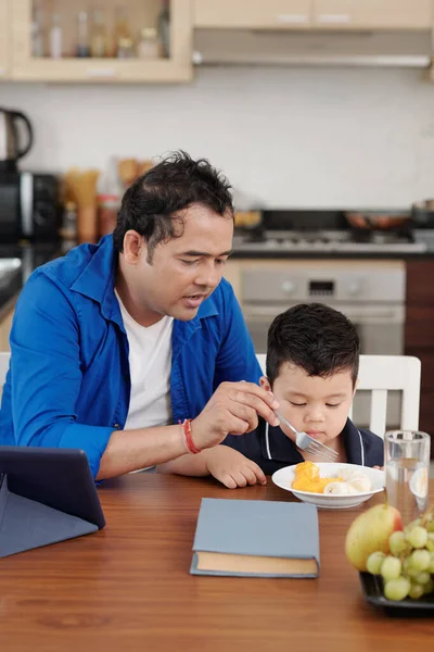 Father Talking Son Feeding Him Fruit Slices Lunch Home — Stockfoto