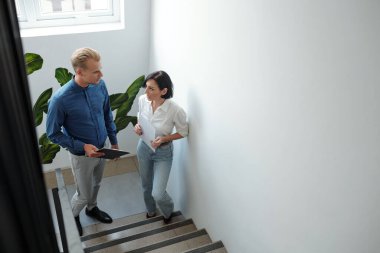 Ciddi genç iş arkadaşları ofis binasının basamaklarında dikilip toplantıdan sonra ayrıntıları tartışıyorlar.