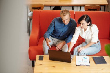 Yerel kahve dükkanında çalışan genç iş adamları sunumu dizüstü bilgisayardan izliyor ve raporları analiz ediyorlar.