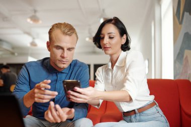 İş kadını, kahve dükkanında gündelik toplantılar yaparken iş arkadaşına proje yönetimi için yeni mobil başvuru gösteriyor