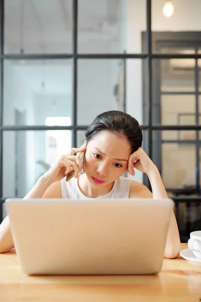 ノートパソコンの画面で彼のレポートを読んだ後 同僚に電話をかける深刻な女性起業家 — ストック写真