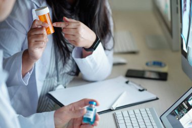 Hasta hasta için hastane masasında otururken ilaç ya da takviye seçen doktorlardan oluşan bir ekip