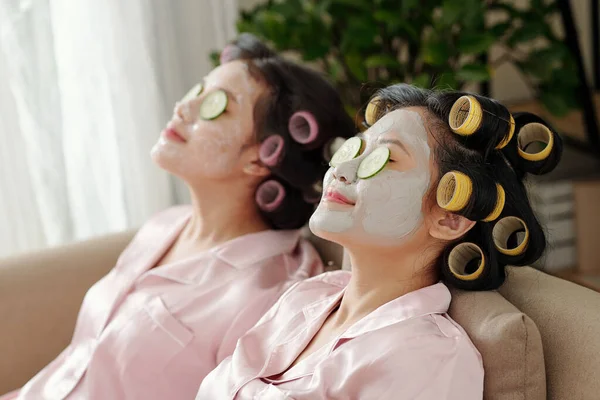 Jovens Mulheres Bonitas Com Rolos Cabelo Relaxando Sofá Com Máscaras — Fotografia de Stock