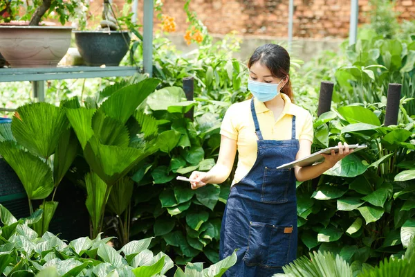 Vrouwelijke Kwekerij Werknemer Beschermende Masker Controleren Lijst Van Planten Moet — Stockfoto