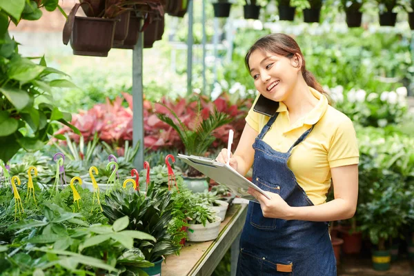 Lächelnde Hübsche Gartencenter Mitarbeiterin Telefoniert Mit Kunden Und Macht Sich — Stockfoto