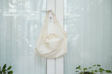 Evin giriş kapısının kolunda yeniden kullanılabilir tekstil alışveriş çantası asılı.