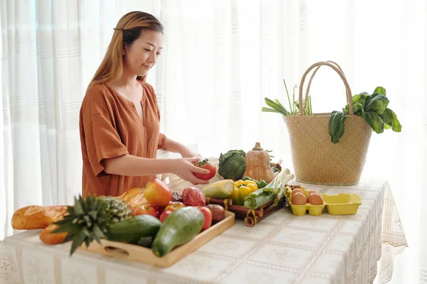 一个微笑的年轻女人打开她在当地市场上买的购物袋 把水果和蔬菜放在盘子里 — 图库照片