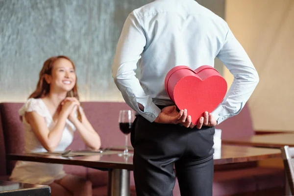 男人在餐桌前 背着女友藏着浪漫的礼物 — 图库照片