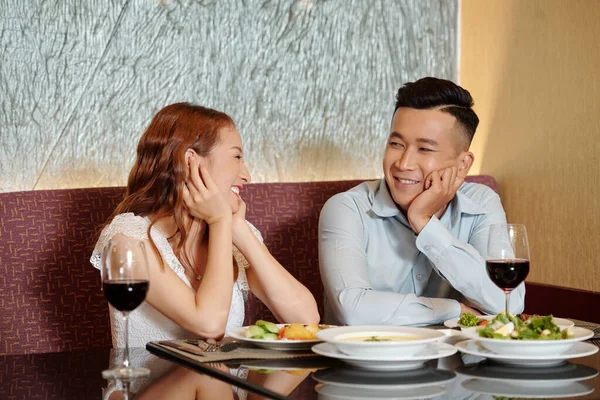 陽気な若者と女性がおいしい料理とレストランのテーブルに座って お互いを見て — ストック写真